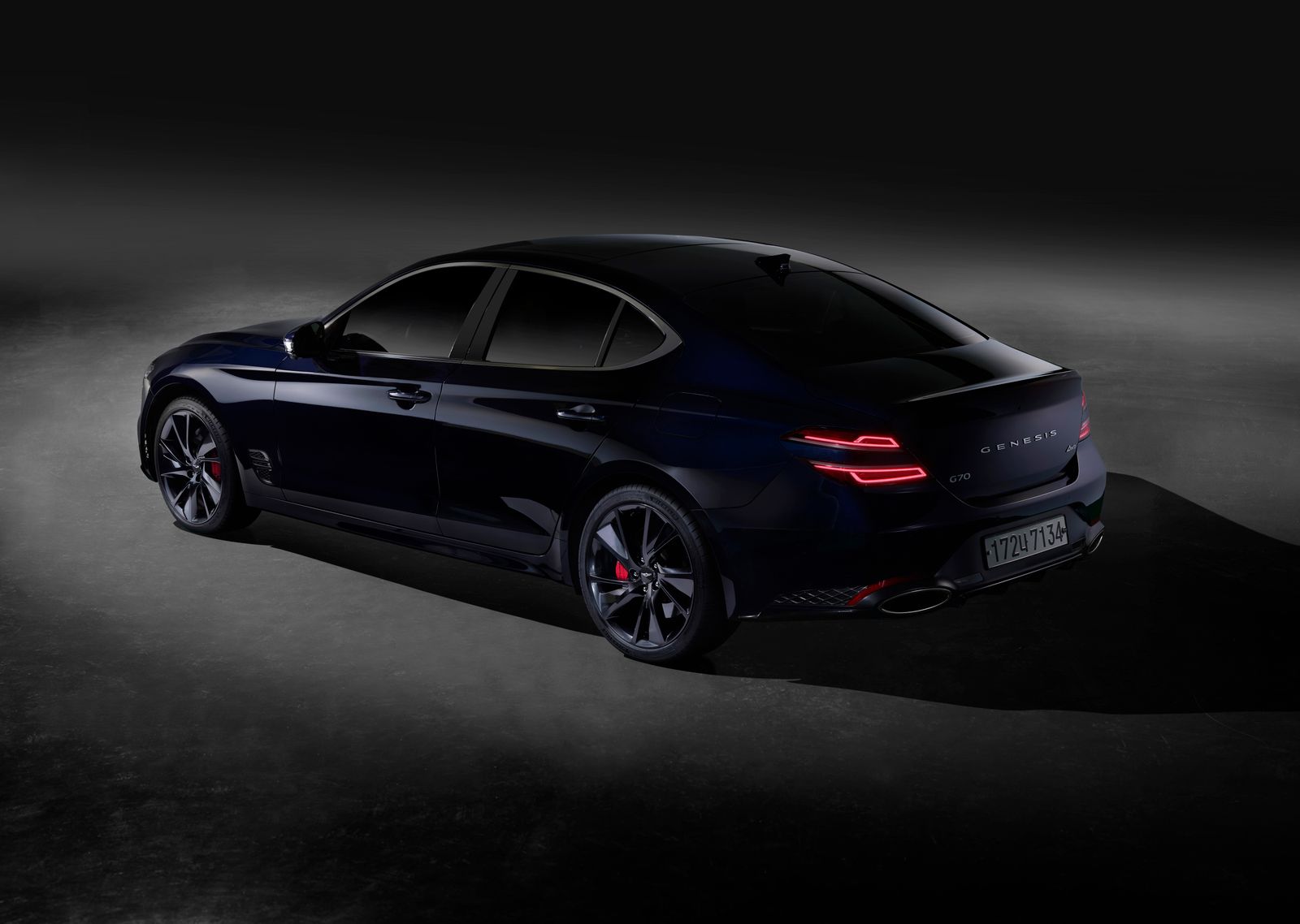Glossy black car under bay lights at Gleam Garage